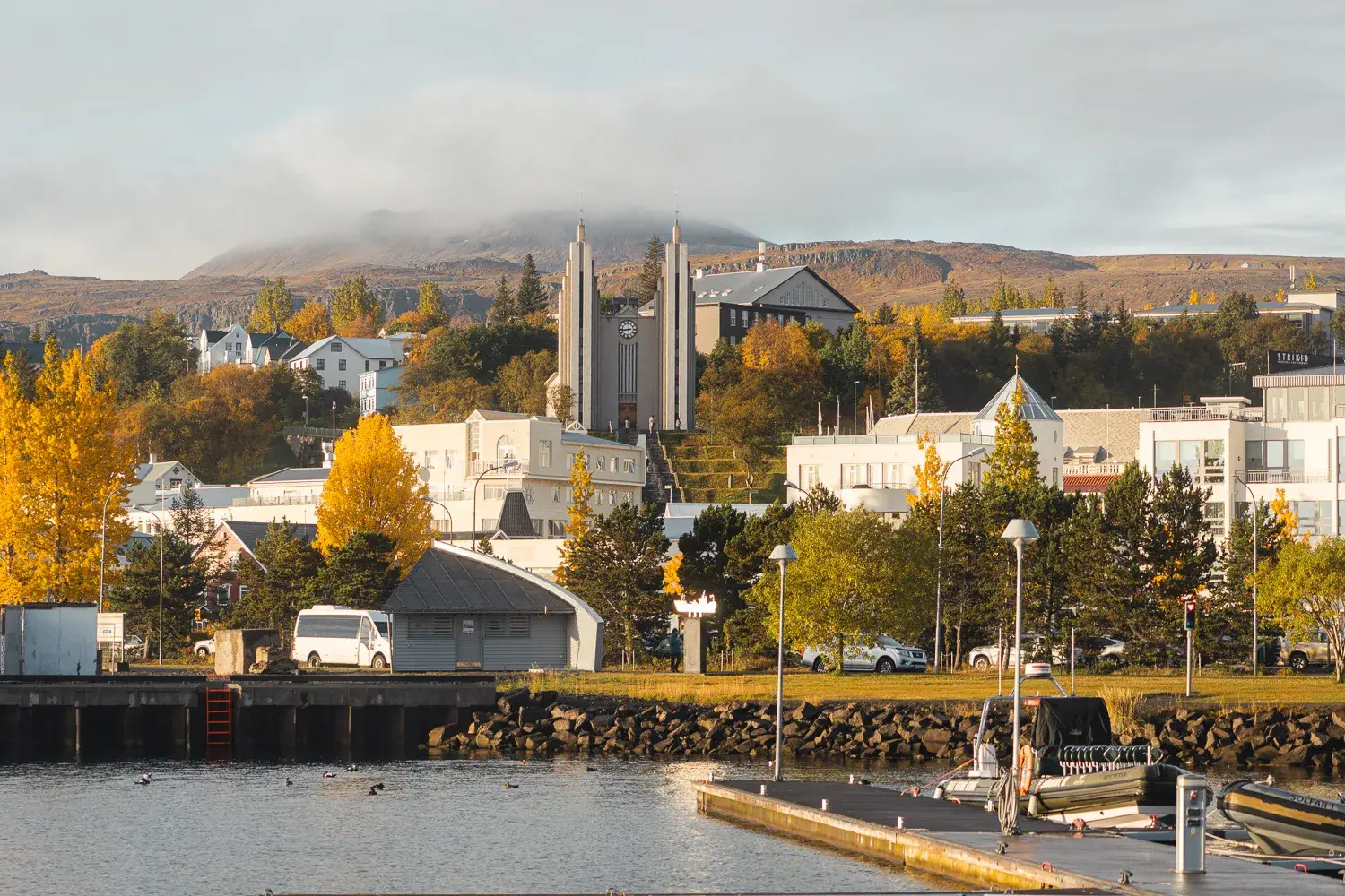 ciudad de Akureyri desde el puerto durante el otoño con los arboles con hojas amarillas y la iglesia de fondo