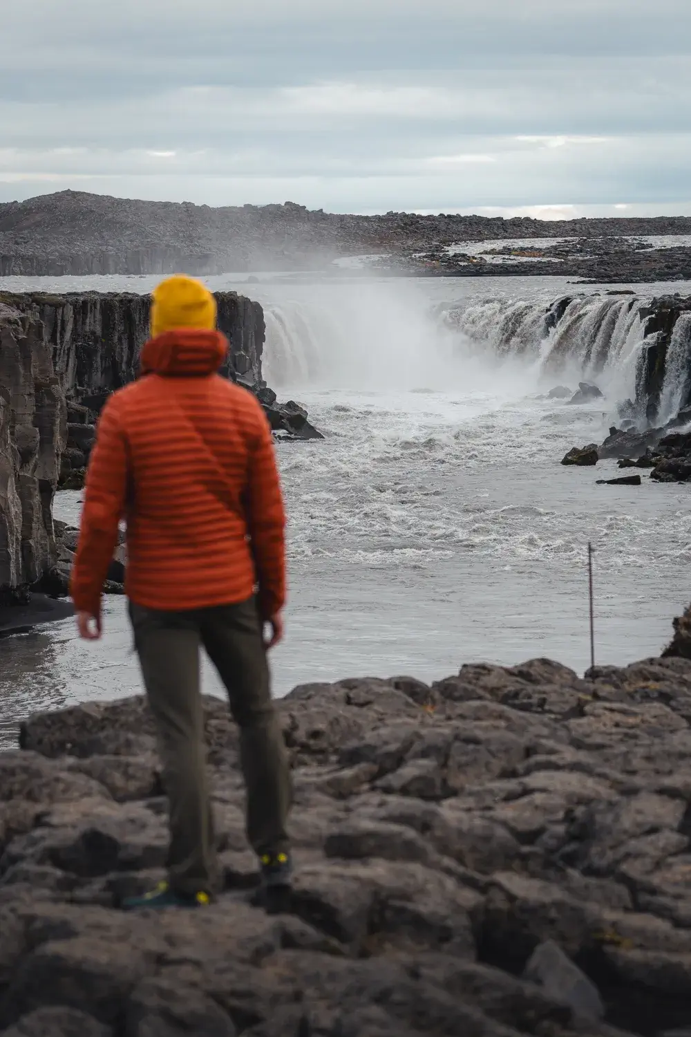 David en primer plano desenfocado y la cascada Selfoss enfocada al fondo, una de las maravillas naturales que ver en el norte de Islandia.