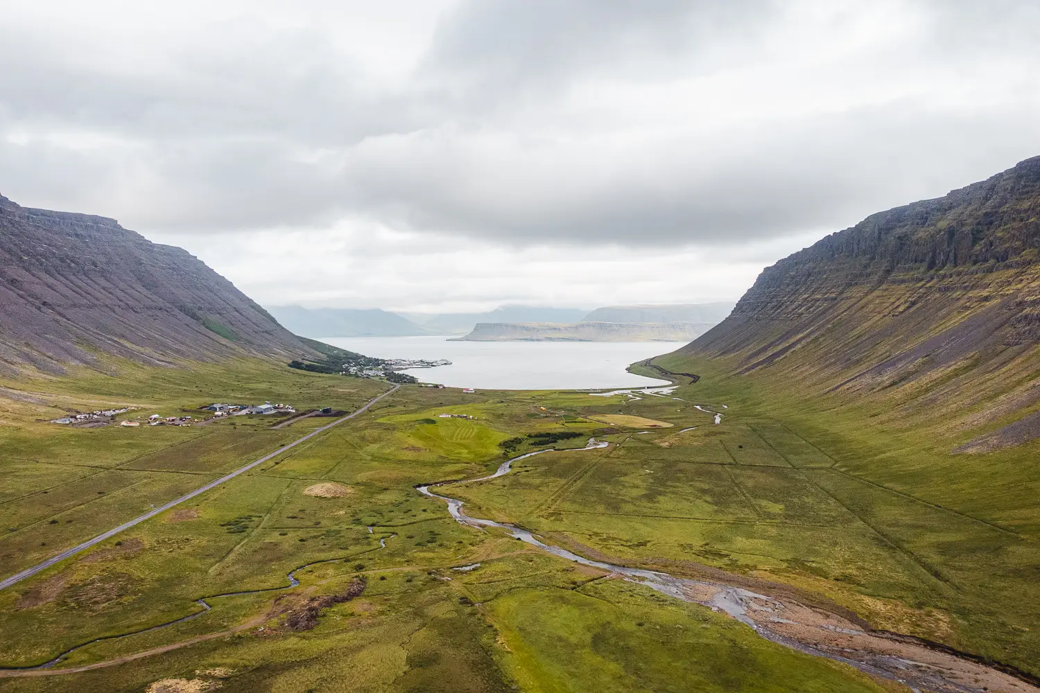 Vista de dron de uno de los Westfjords de Islandia con un prado verde, ríos que serpentean y las montañas que rodean el valle.