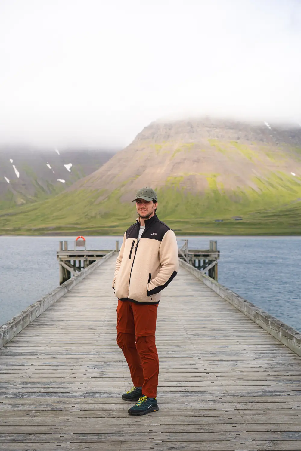 David en el muelle de  Önundarfjörður durante el verano, donde se ve la montaña verde.