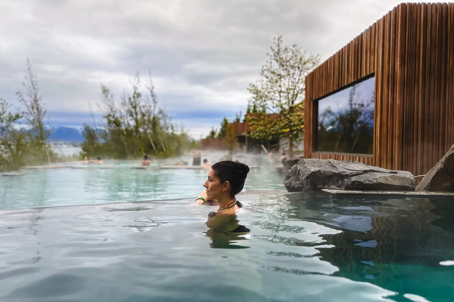 Silvia disfrutando de las aguas geotermales de Forest Lagoon, rodeada de vegetación y con vistas al fiordo de Eyjafjörður.