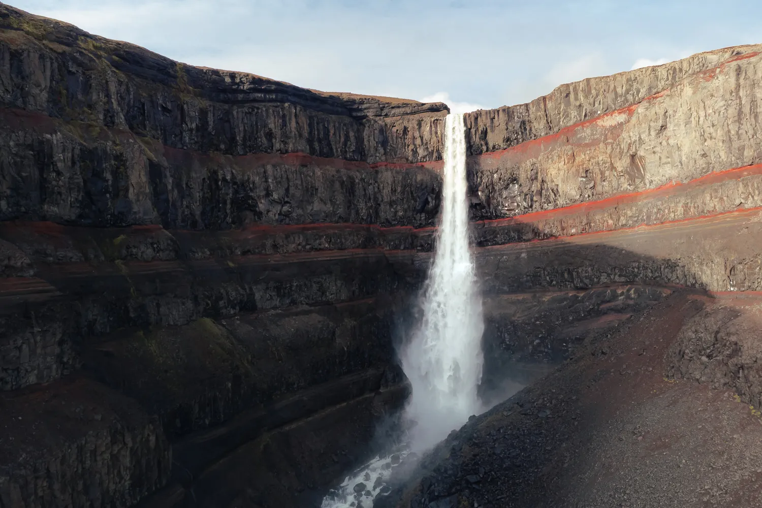 Hengifoss, una de las cascadas más altas de Islandia, rodeada de paredes rocosas con características franjas rojizas