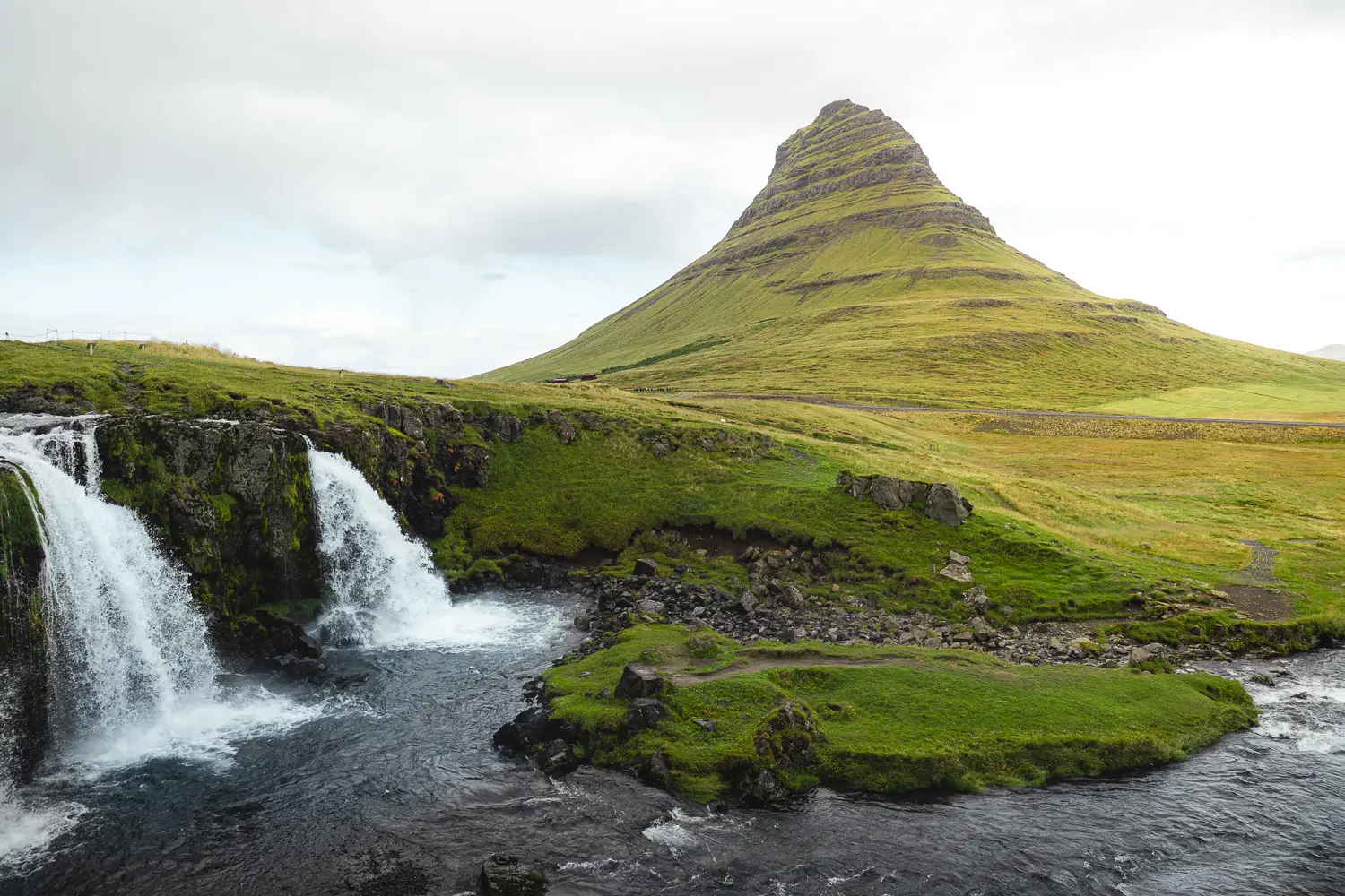 Montaña Kirkjufell junto a la cascada Kirkjufellsfoss, uno de los paisajes más icónicos de la península de Snæfellsnes, Islandia.