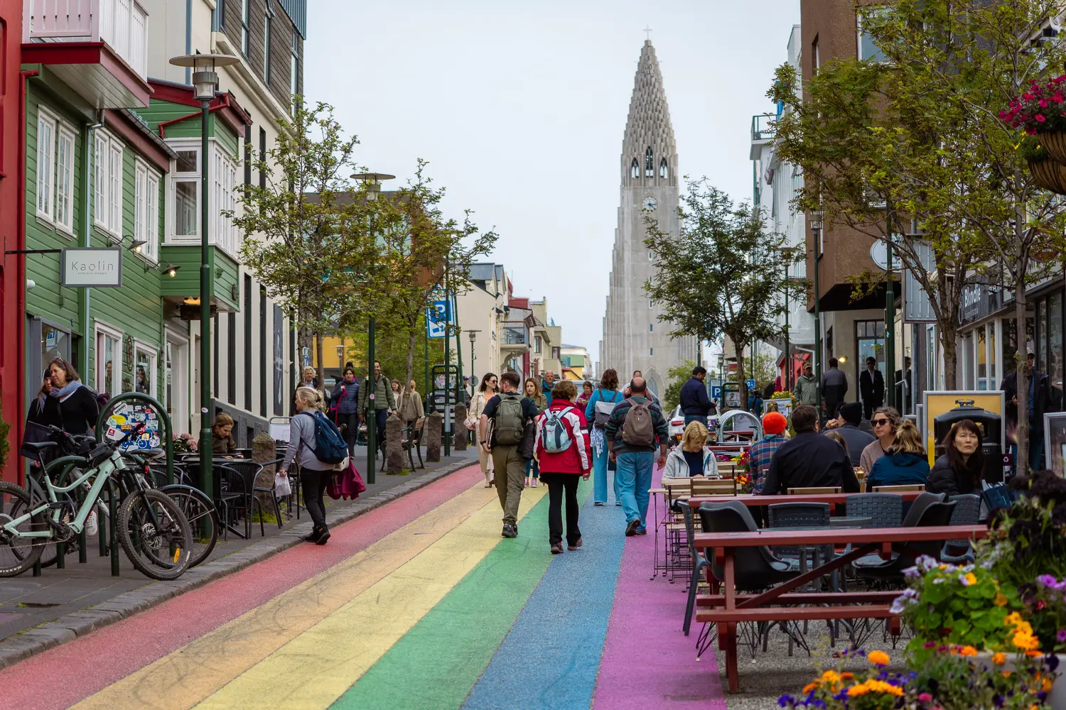 Colorida calle con arcoíris pintado en el suelo y la iglesia de Hallgrímskirkja de fondo, emblema de la ciudad de Reykjavík.