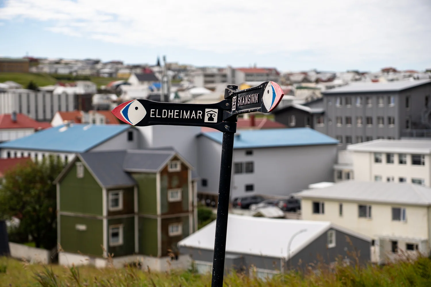 Señal turística en las Islas Vestman, Islandia con edificios al fondo 